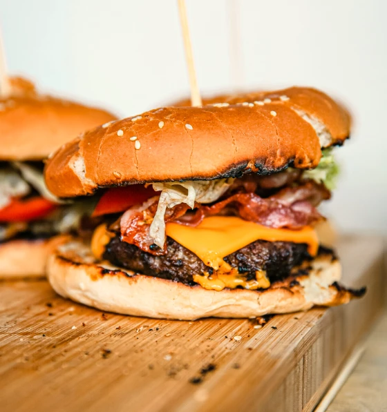 Burger steak et bacon servi sur une planche, illustrant le travail de Ty'Djo, foodtruck de burgers dans les Côtes-d'Armor.