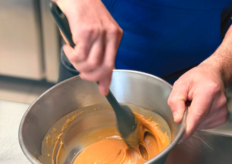 Jonathan, artisan traiteur pâtissier, en pleine préparation d'une ganache caramel dans son atelier dans les Côtes-d'Armor.